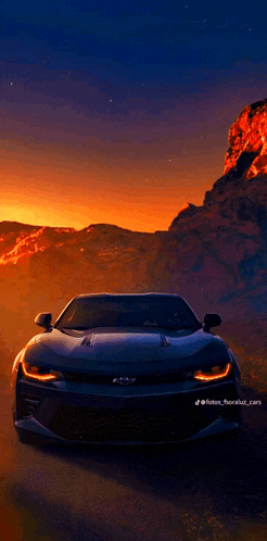 a chevrolet camaro is driving through a desert at sunset