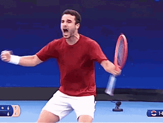 a man in a red shirt is holding a tennis racquet and celebrating