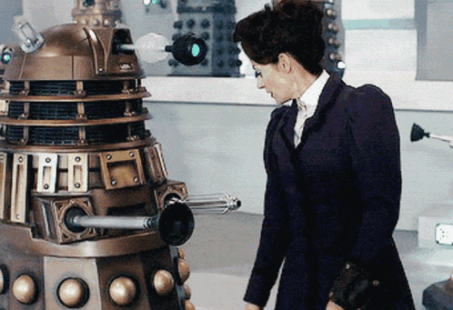 a woman is standing next to a robot that has a gun on it 's head