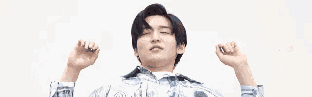 a young man with his arms outstretched is wearing a blue shirt with a pattern on it .
