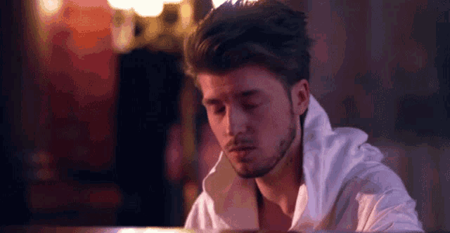 a young man in a white shirt is sitting at a piano