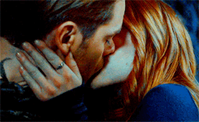 a man and woman are kissing with the woman wearing a ring on her finger