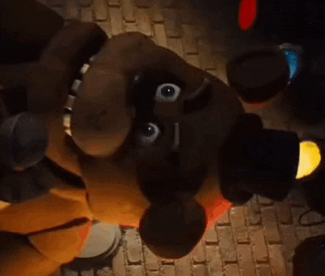 a close up of a stuffed animal in a dark room with a brick wall .