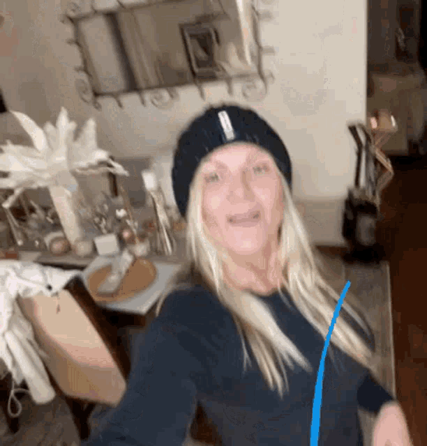 a woman wearing a black beanie and a blue purse is standing in a living room .