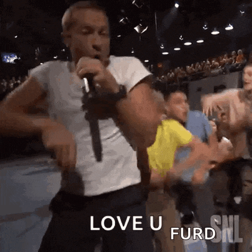 a man is singing into a microphone in front of a crowd and says love u furd