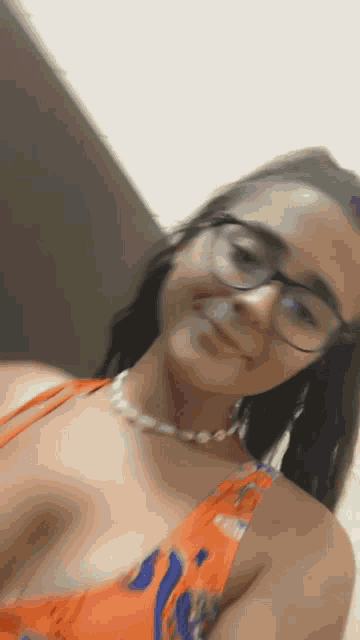 a woman wearing glasses and a necklace is smiling for the camera