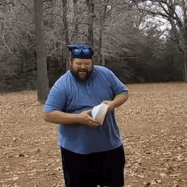 a man with a beard wearing a graduation cap is holding a book in a field .