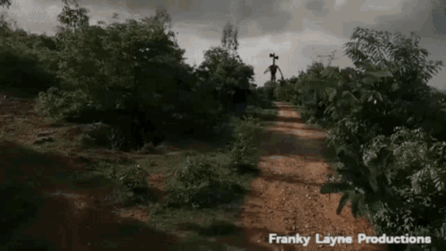a siren head is standing in the middle of a dirt road in the woods .