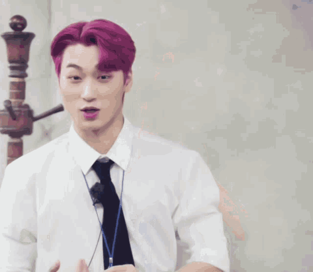 a man with pink hair is wearing a white shirt and a black tie