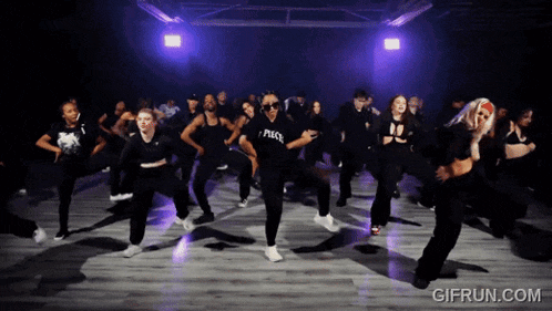 a group of people are dancing in a dark room and one of them is wearing a shirt that says peace