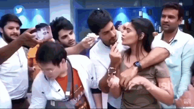 a man is kissing a woman on the cheek while a group of people are taking pictures of them .