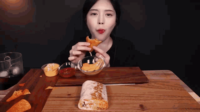 a woman is eating a burrito with tortilla chips
