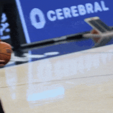 a basketball is being thrown on a court with a cerebral sign in the background