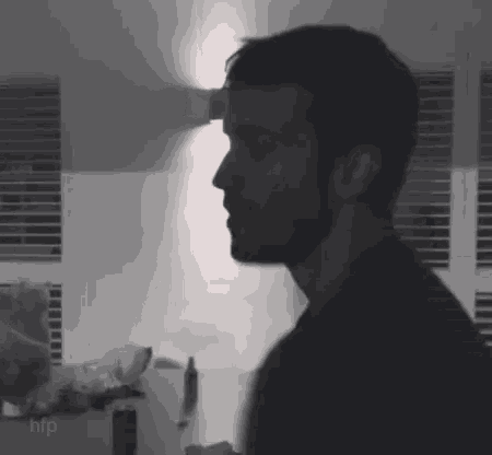 a man with a beard is standing in front of a window in a black and white photo