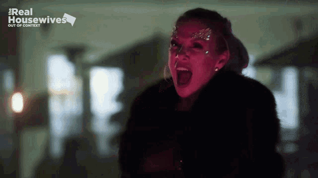 a woman in a fur coat is screaming in front of a real housewives logo