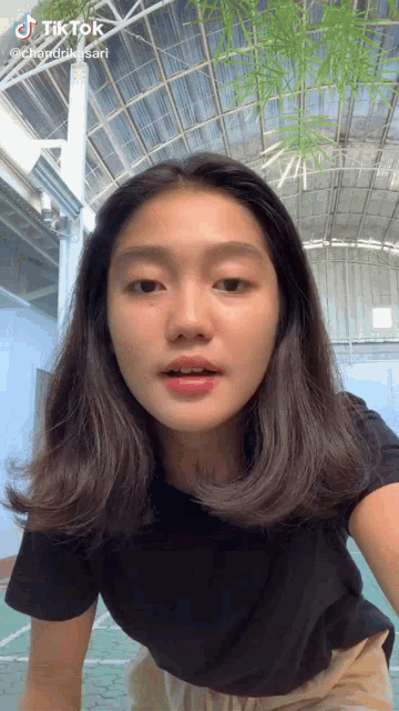 a young woman is making a funny face while wearing a black shirt and khaki pants .