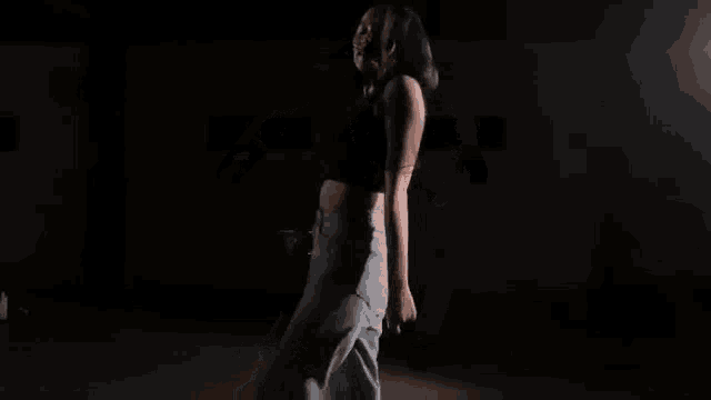 a woman is dancing in a dark room in a dimly lit room .