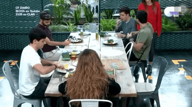 a group of people are sitting at a long table with a sign that says ot diario on it