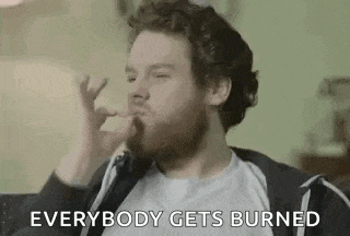 a man with a beard is smoking a cigarette and says `` everybody gets burned '' while sitting down .