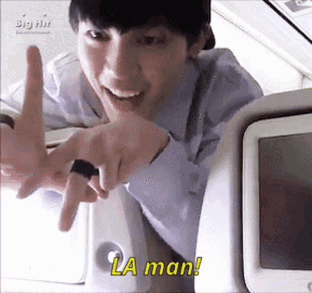 a man with a ring on his finger is smiling and pointing at the camera with the words la man below him