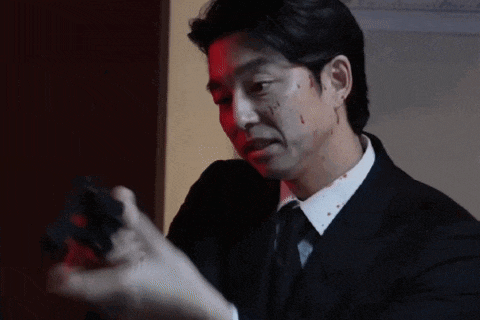 a man in a suit and tie with blood on his face is holding a gun