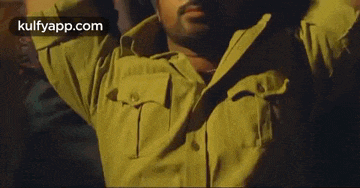 a man in a police uniform is standing with his arms outstretched in a dark room .