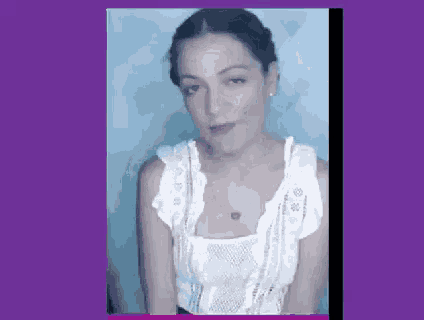 a woman in a white tank top is making a face