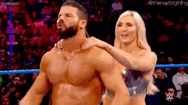 a man and a woman are standing in a wrestling ring . the woman is holding the man 's neck .