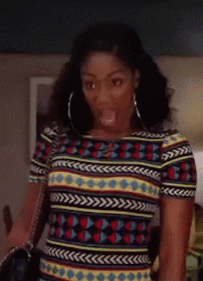 a woman wearing a colorful shirt and hoop earrings is making a face .