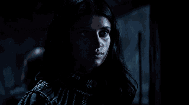 a woman in a dark room looks at the camera