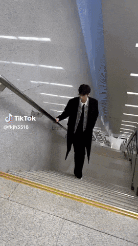 a man in a suit and tie is walking down a set of stairs