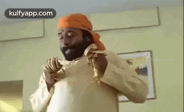 a man with a beard is wearing a turban and a gold chain around his neck .
