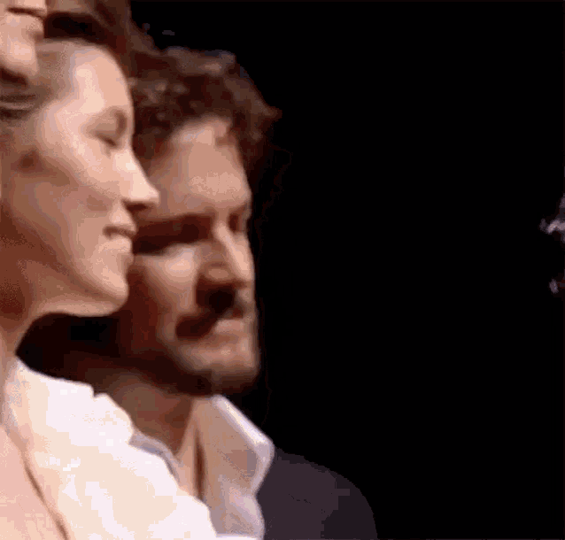 a man and a woman are standing next to each other on a stage in a dark room .