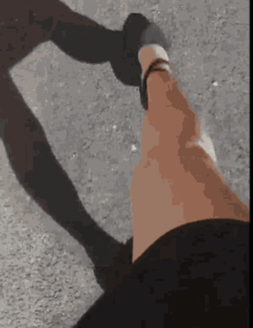a person is holding another person 's hand with their shadow on the ground .