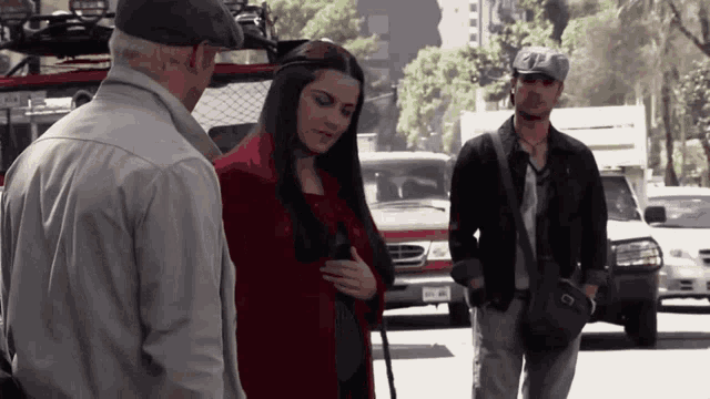 a woman in a red coat is talking to a man and another man