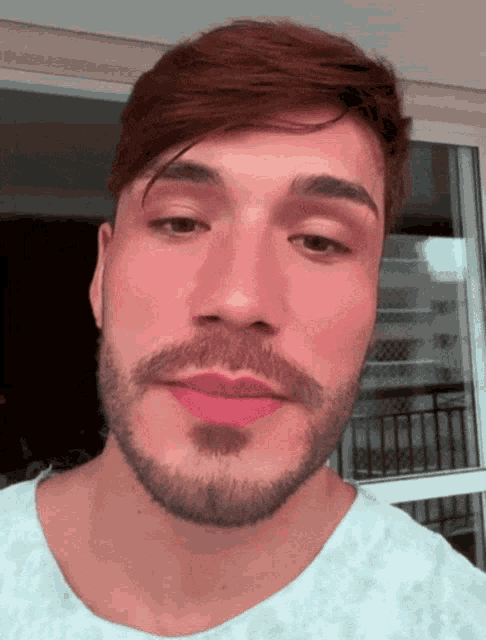 a man with a beard and red lipstick on his lips looks at the camera