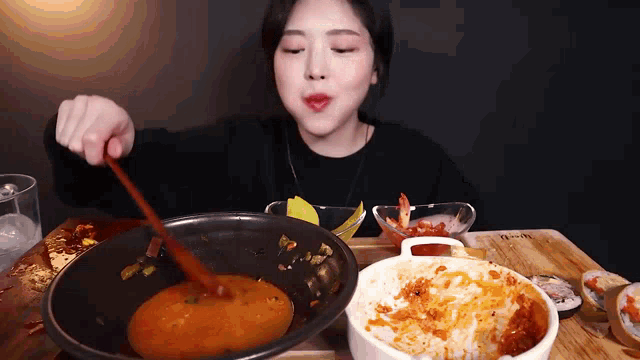 a woman is eating food with a wooden spoon