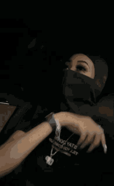 a woman wearing a black mask is giving a thumbs up .