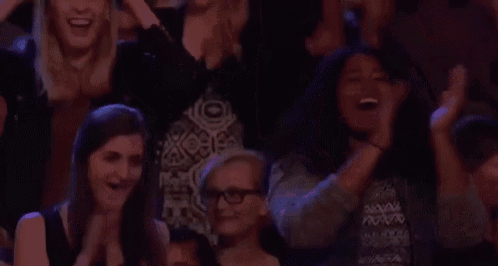 a group of people are sitting in a theatre applauding a performance .