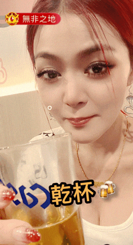 a woman with red hair is holding a glass of beer with asian writing on it