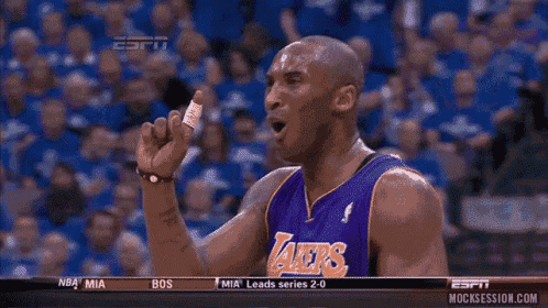 a basketball player wearing a lakers jersey is pointing at another player