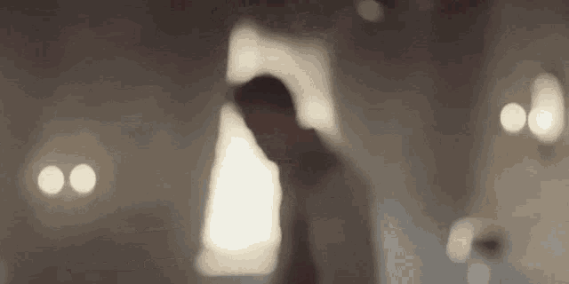 a blurry picture of a man standing in a room with a window .