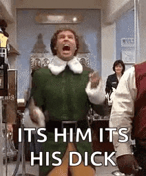 a man in a green elf costume is screaming while standing in a room with other people .