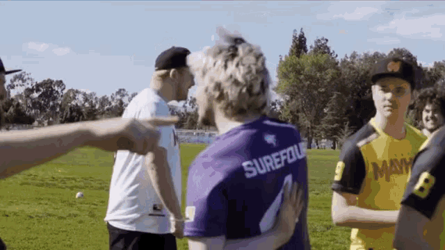 a man in a purple shirt with the name surefoil on it is hugging another man