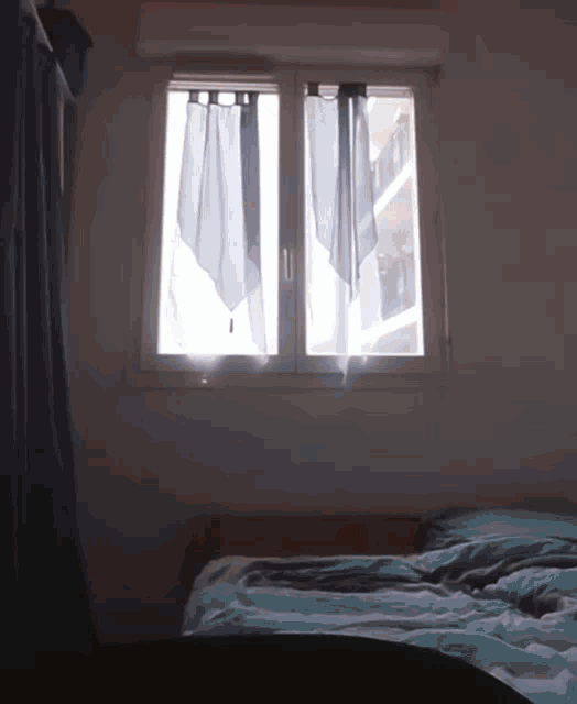 a bedroom with a bed and a window with curtains hanging on it