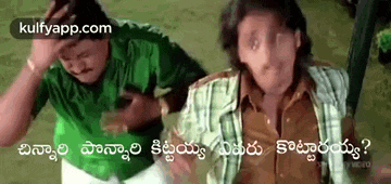 two men are sitting next to each other on a grassy field and one of them is holding his head .
