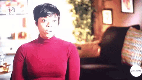 a woman in a red turtleneck is sitting in front of a lifetime logo