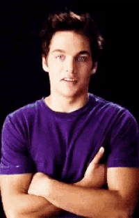 a young man wearing a purple shirt with his arms crossed