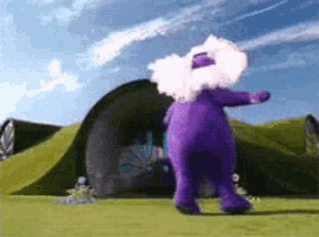 a purple teletubbies character is dancing in front of a tunnel .