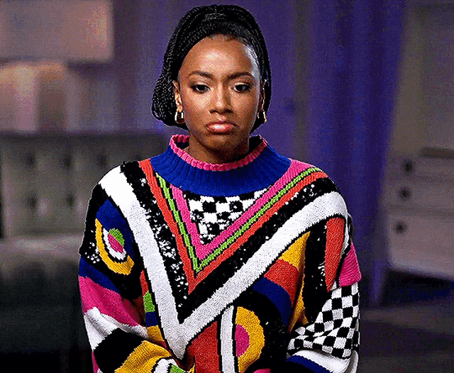 a woman is wearing a colorful sweater and making a funny face